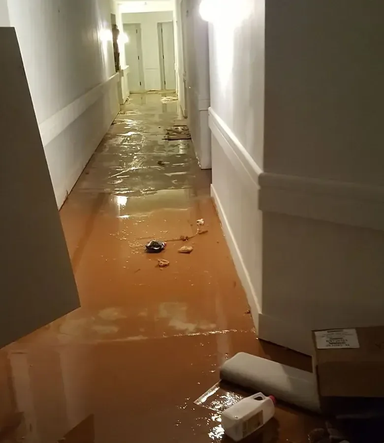 Muddy water and scattered debris covering an interior hallway floor